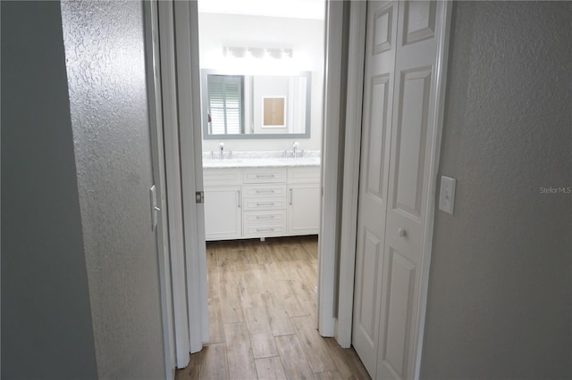 hallway with sink and light wood-type flooring