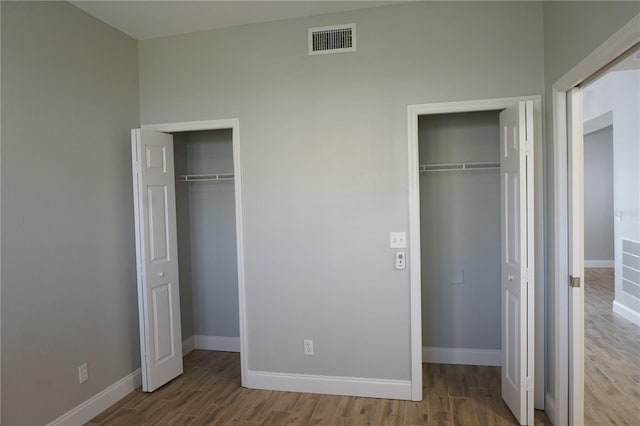 unfurnished bedroom featuring multiple closets and light hardwood / wood-style floors