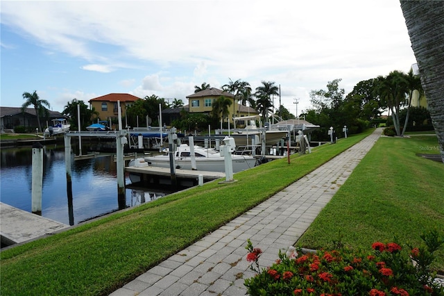 view of dock with a lawn and a water view