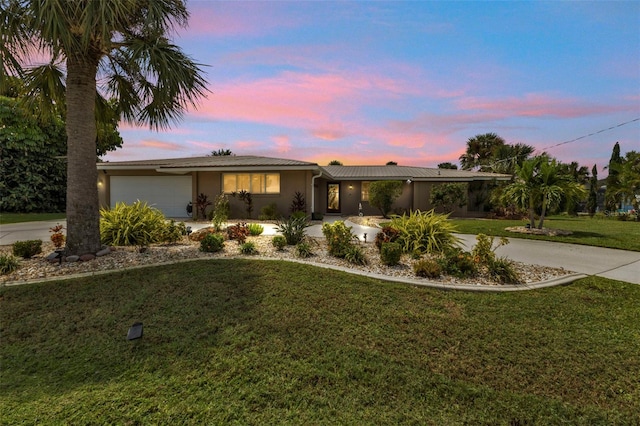 ranch-style home with a garage and a yard