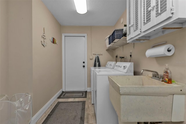 laundry area featuring a textured ceiling, cabinets, hardwood / wood-style floors, independent washer and dryer, and sink