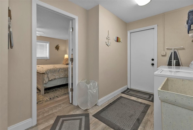 doorway with light hardwood / wood-style floors, washing machine and clothes dryer, and sink