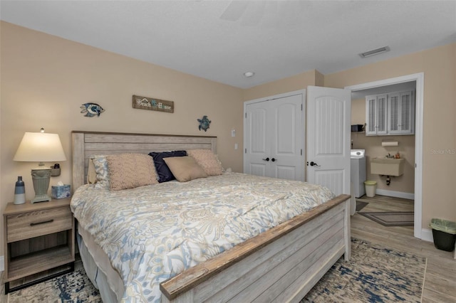 bedroom featuring light wood-type flooring, washer / dryer, and sink