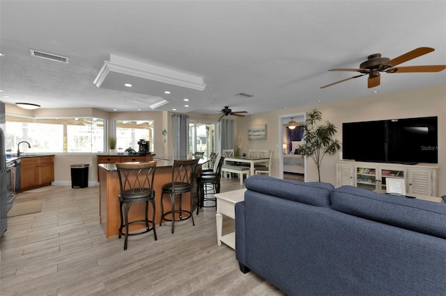 living room featuring ceiling fan, sink, and light hardwood / wood-style flooring