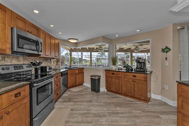 kitchen featuring dark stone countertops, light hardwood / wood-style flooring, stainless steel appliances, and sink