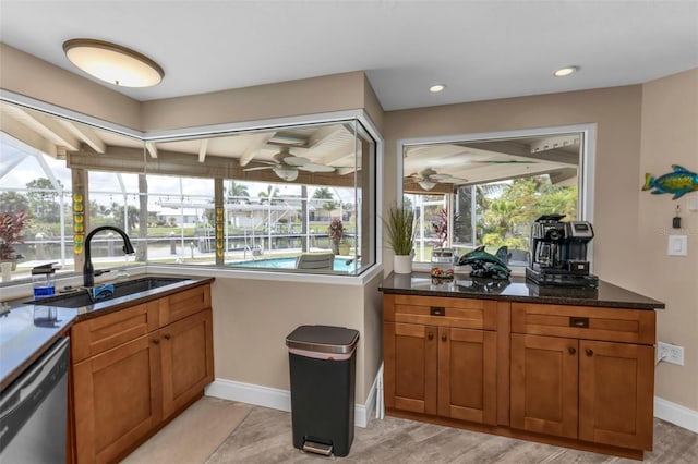 kitchen with dishwasher, light hardwood / wood-style floors, ceiling fan, sink, and dark stone countertops