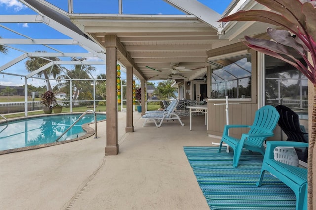 view of swimming pool featuring glass enclosure, a patio, and ceiling fan