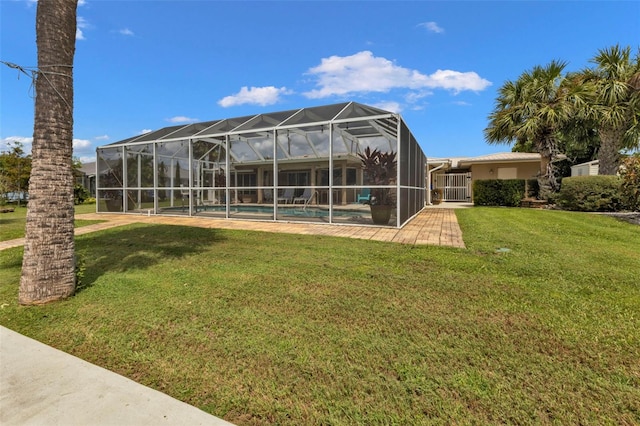 back of property featuring glass enclosure and a lawn