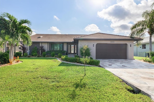 ranch-style house featuring a garage and a front lawn