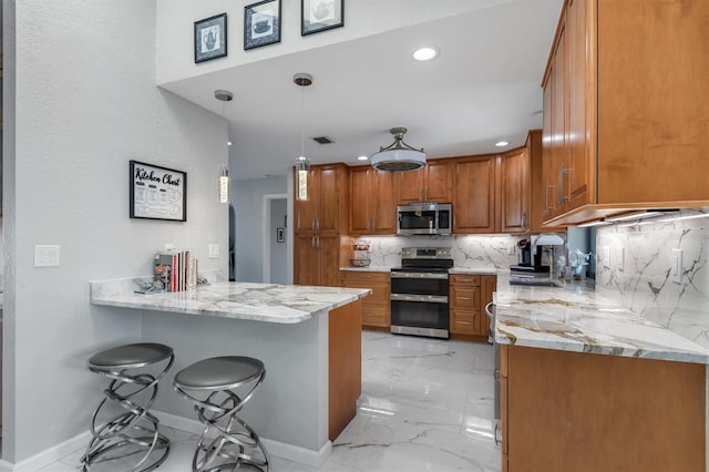 kitchen with kitchen peninsula, tasteful backsplash, stainless steel appliances, decorative light fixtures, and a breakfast bar area