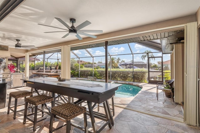 sunroom featuring a wealth of natural light, ceiling fan, and a pool