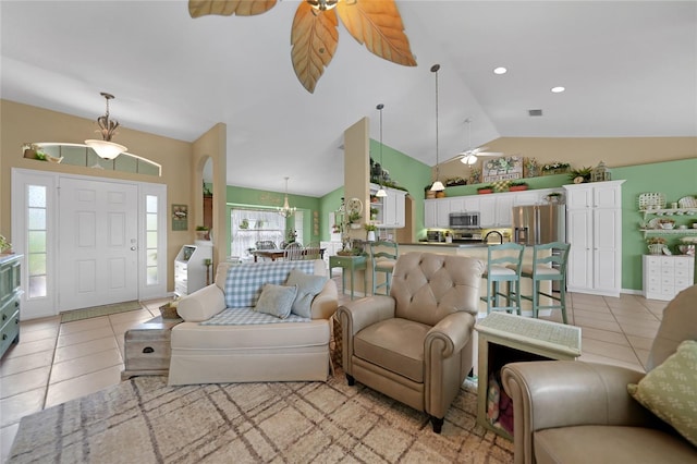 living room featuring ceiling fan with notable chandelier, lofted ceiling, and light tile patterned floors