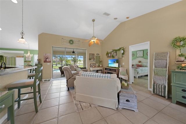 living area featuring light tile patterned floors, high vaulted ceiling, ceiling fan with notable chandelier, and visible vents
