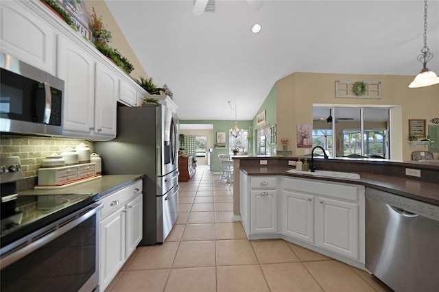 kitchen featuring sink, lofted ceiling, white cabinetry, stainless steel appliances, and decorative light fixtures