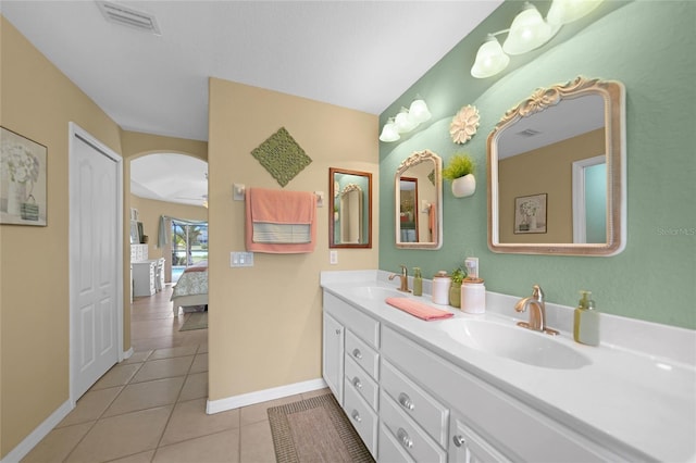 ensuite bathroom with double vanity, visible vents, a sink, and tile patterned flooring