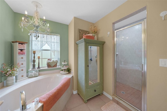 bathroom with tile patterned flooring, a notable chandelier, a garden tub, and a shower stall