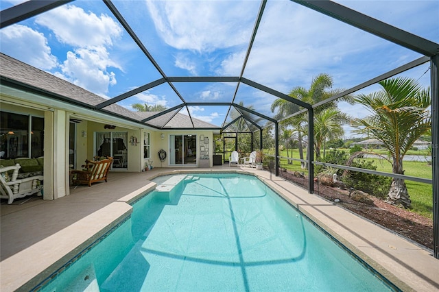 pool featuring glass enclosure, a patio, and a ceiling fan