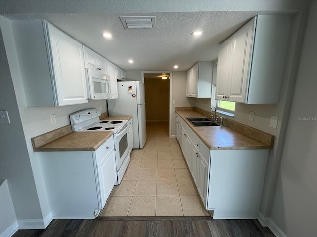 kitchen featuring white appliances, sink, light tile patterned floors, a textured ceiling, and white cabinetry