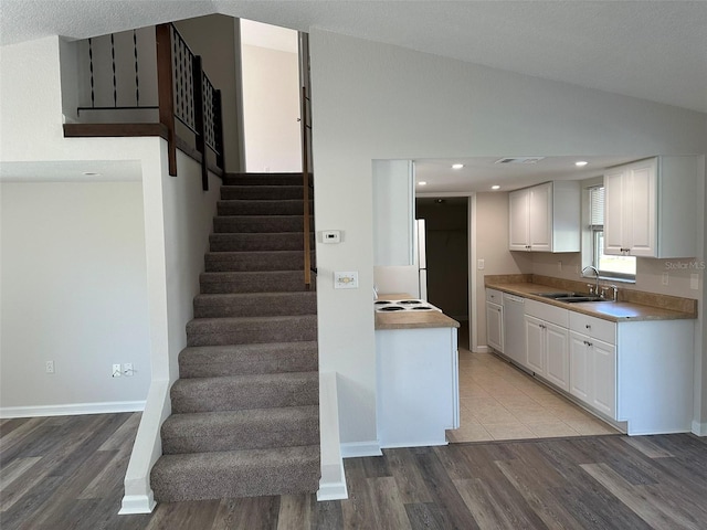 kitchen featuring white appliances, sink, light hardwood / wood-style floors, white cabinetry, and lofted ceiling