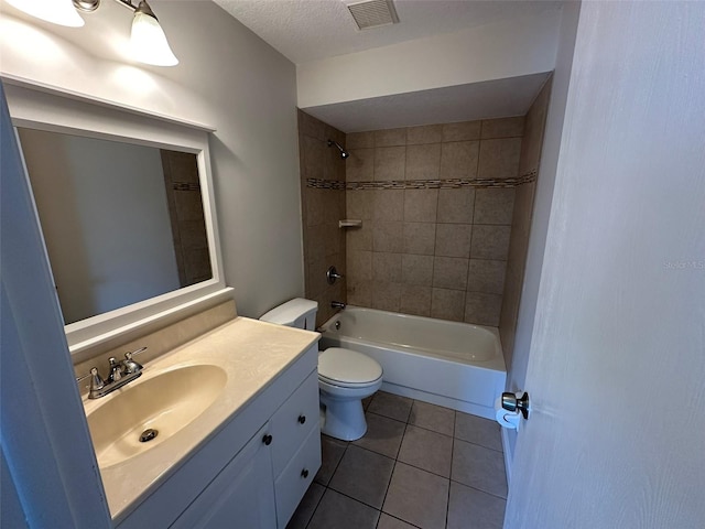 full bathroom featuring vanity, tiled shower / bath combo, a textured ceiling, tile patterned flooring, and toilet