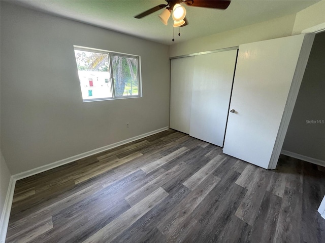 unfurnished bedroom with ceiling fan, dark hardwood / wood-style flooring, and a closet