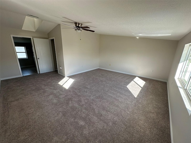 carpeted spare room featuring a textured ceiling, vaulted ceiling, and plenty of natural light