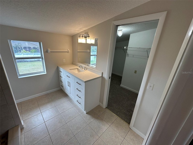 bathroom featuring tile patterned floors, vanity, a textured ceiling, and vaulted ceiling