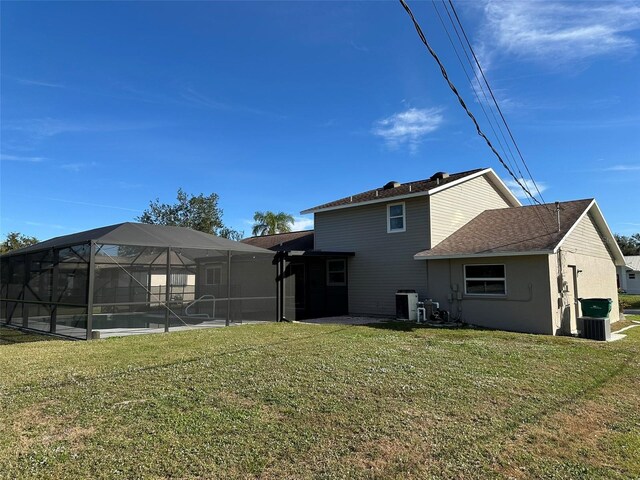 rear view of property featuring central AC, a yard, and glass enclosure