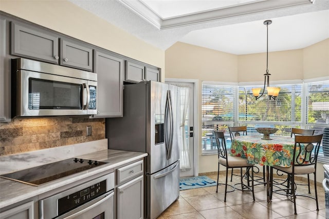 kitchen featuring decorative light fixtures, appliances with stainless steel finishes, light tile patterned floors, and a wealth of natural light