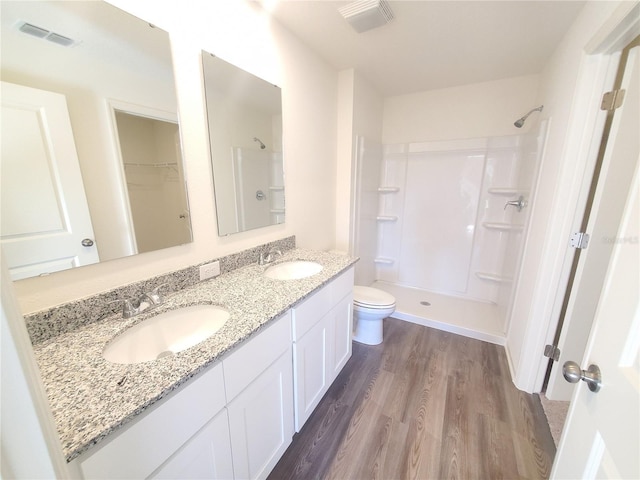 bathroom featuring hardwood / wood-style flooring, toilet, a shower, and vanity