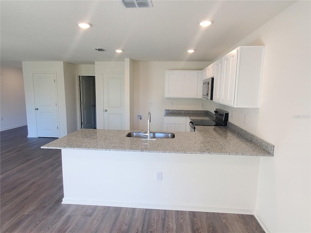 kitchen with white cabinets, stove, kitchen peninsula, and sink