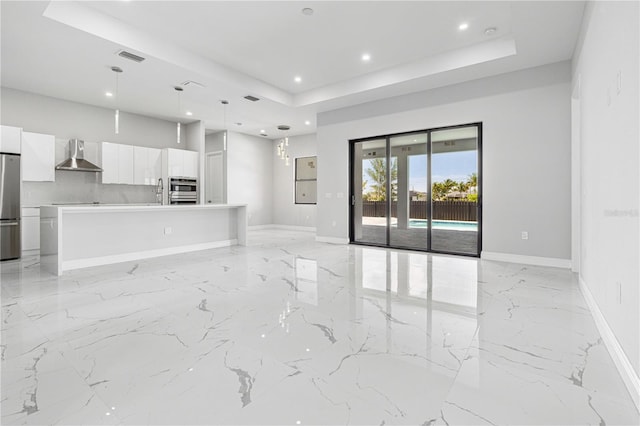 unfurnished living room featuring a raised ceiling and sink