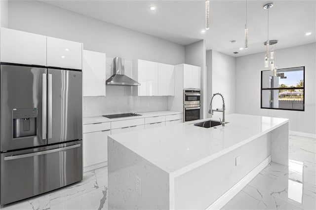 kitchen featuring wall chimney exhaust hood, an island with sink, decorative light fixtures, and stainless steel appliances