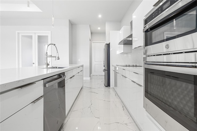 kitchen with light stone counters, sink, appliances with stainless steel finishes, and white cabinets