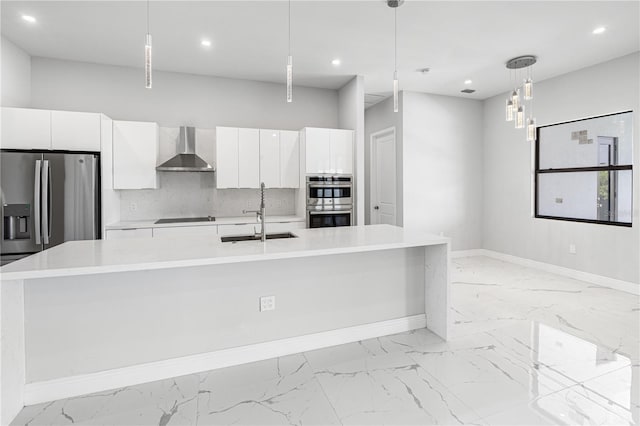 kitchen with a kitchen island with sink, decorative light fixtures, sink, and wall chimney range hood