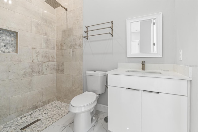 bathroom with vanity, toilet, and tiled shower