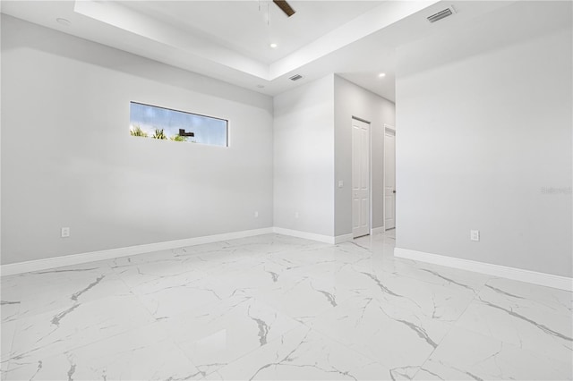 spare room featuring a tray ceiling and ceiling fan