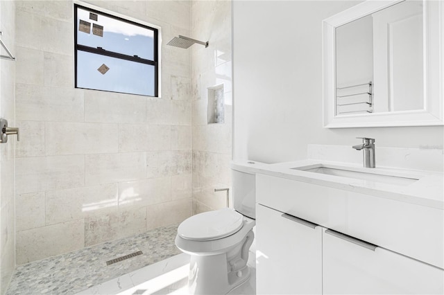 bathroom featuring vanity, toilet, and tiled shower