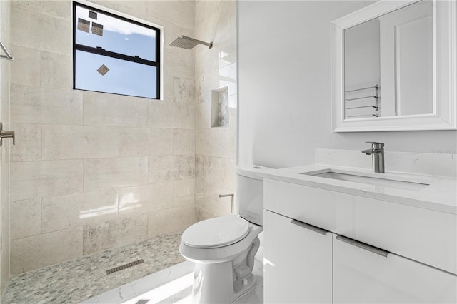 bathroom featuring vanity, toilet, and a tile shower