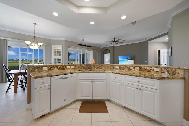 kitchen with white dishwasher, ceiling fan with notable chandelier, white cabinetry, and pendant lighting