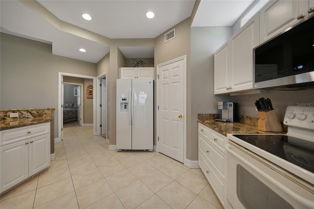 kitchen with white cabinetry, light tile patterned flooring, white appliances, and dark stone countertops