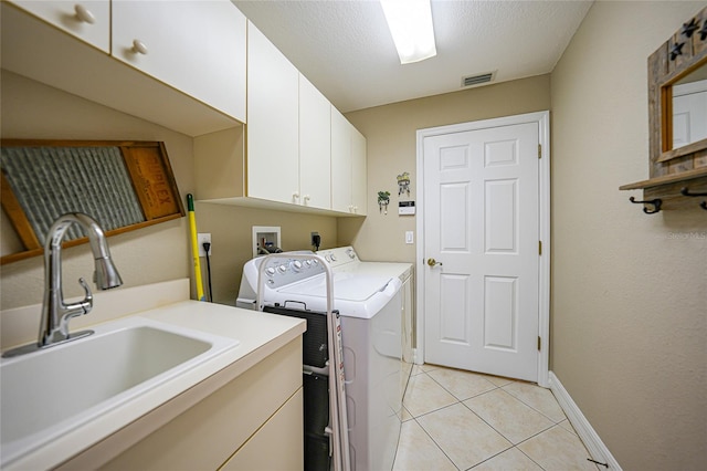 laundry room featuring separate washer and dryer, a textured ceiling, light tile patterned floors, cabinets, and sink