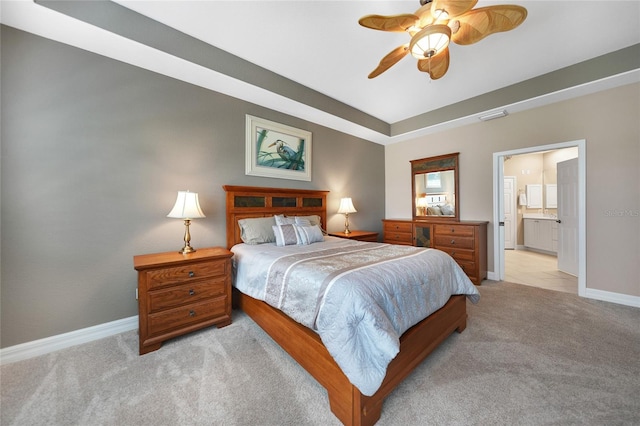 bedroom with light colored carpet, ceiling fan, and connected bathroom