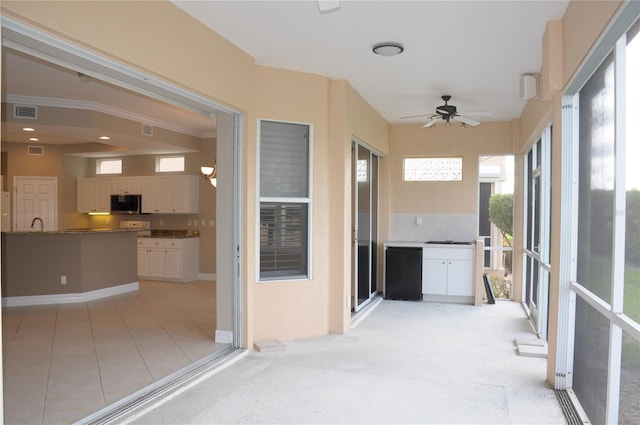 unfurnished sunroom featuring ceiling fan