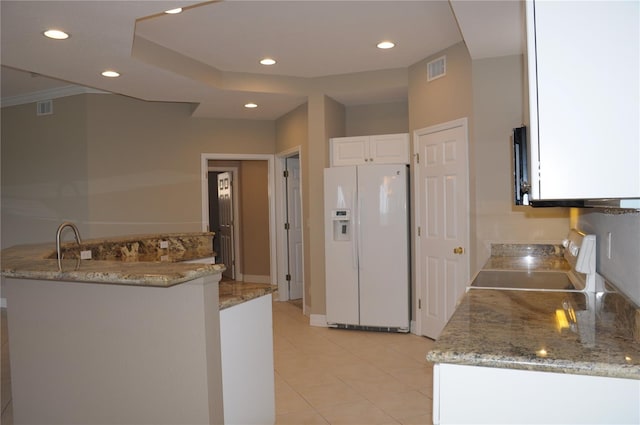 kitchen featuring white refrigerator with ice dispenser, white cabinetry, stainless steel stove, light stone countertops, and kitchen peninsula