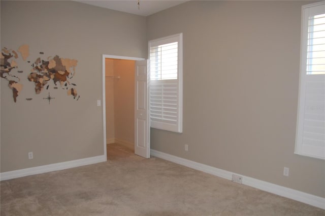 unfurnished room featuring a wealth of natural light and light carpet