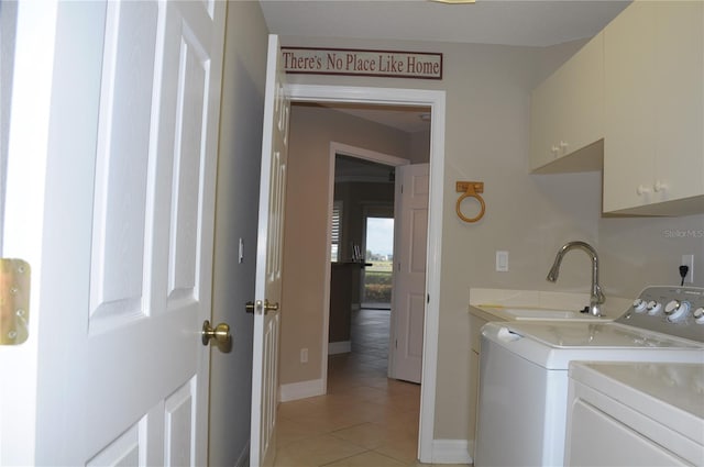 clothes washing area featuring washer and clothes dryer, cabinets, sink, and light tile patterned floors