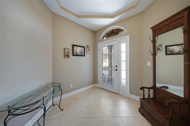 entryway with light tile patterned floors and a tray ceiling