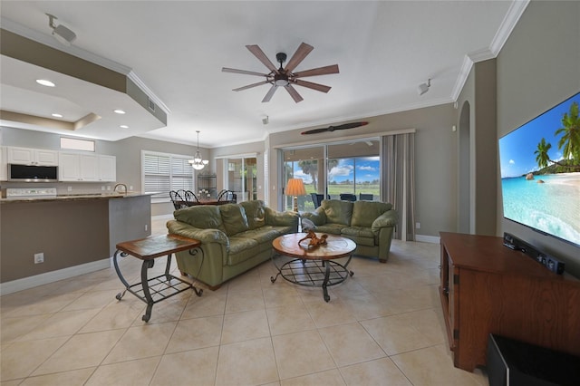 living room with light tile patterned floors, ornamental molding, and ceiling fan with notable chandelier