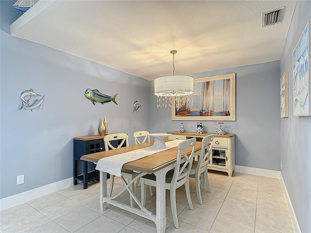 tiled dining space featuring an inviting chandelier and a textured ceiling